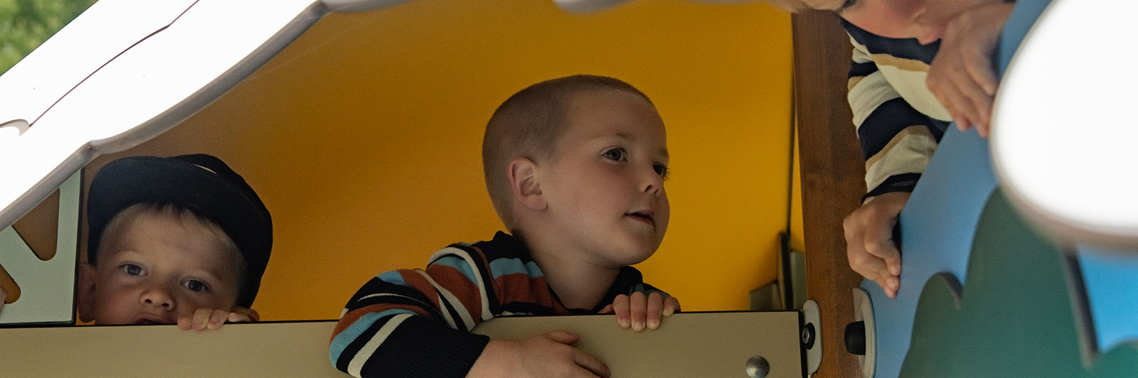 Boys playing with each other in a playhouse.